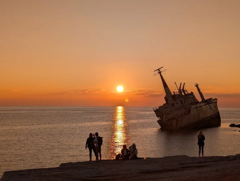 The Edro III Shipwreck at sunset near Paphos, Cyprus, with silhouettes of people watching the sun go down.
