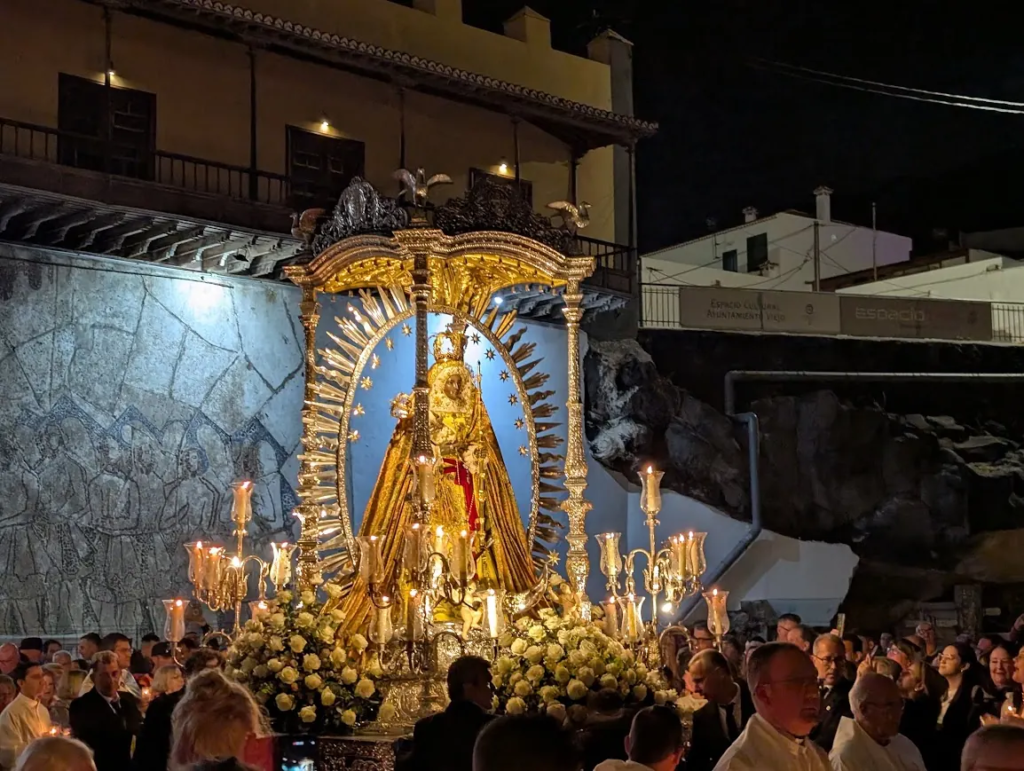 Statue of Our Lady of Candelaria on a candlelit float surrounded by crowds during the evening procession in Candelaria, Tenerife