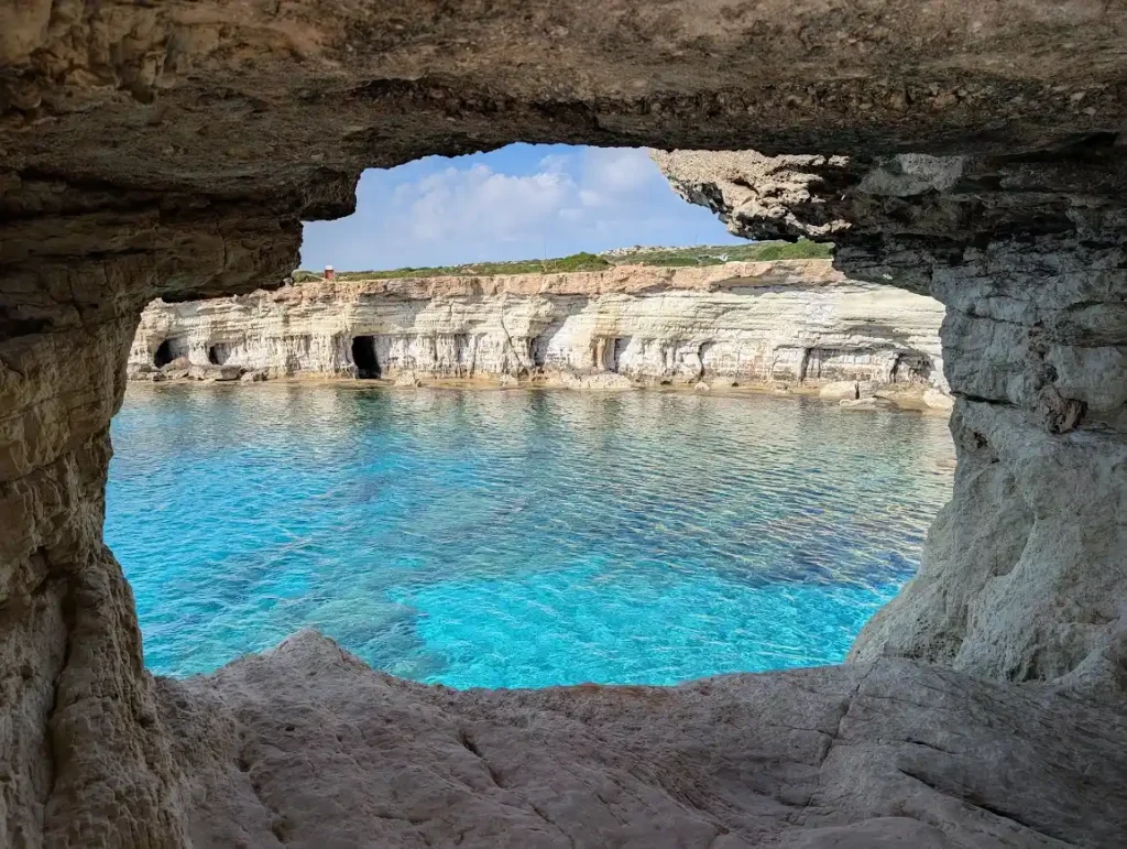 A view from inside a natural rock sea cave looking out toward the bright turquoise waters of the Mediterranean near Cape Greko, Cyprus.