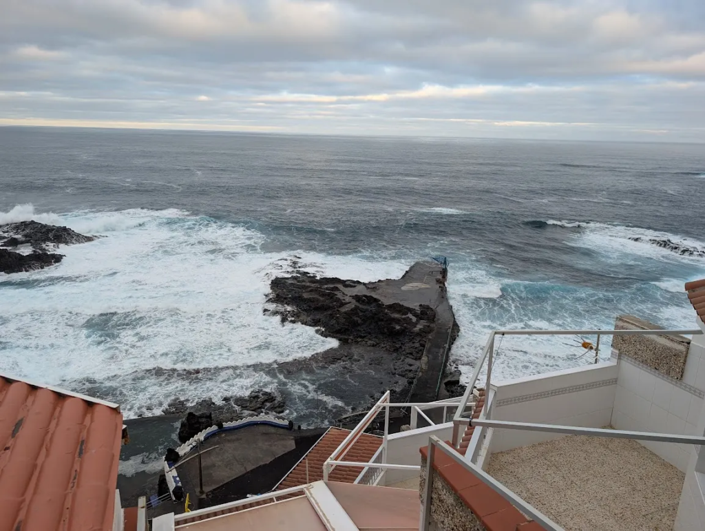 View of Atlantic waves and a lava rock pier from the top-floor apartment terrace in El Pris, Tenerife