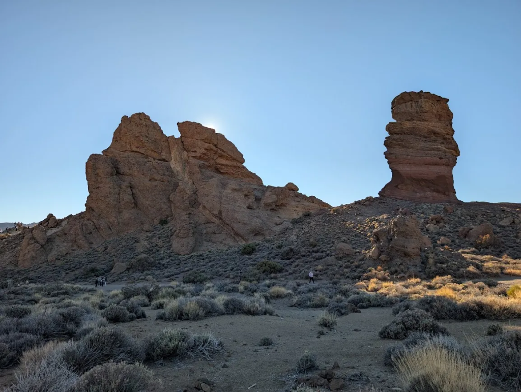 Sunlit red rock formations and a tall stacked rock pillar in Teide National Park, Tenerife