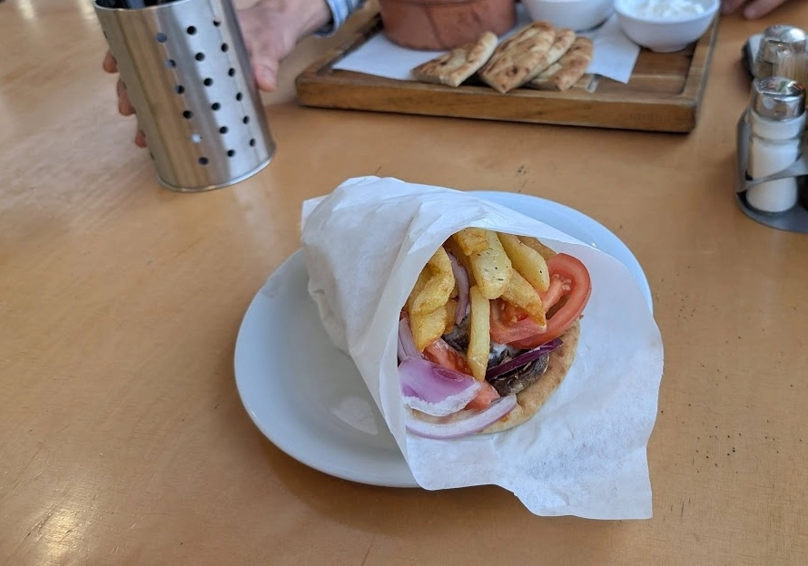 Vegetarian gyro pita wrap with fries, tomato and onion served on a white plate in Larnaca, Cyprus, January 2025.