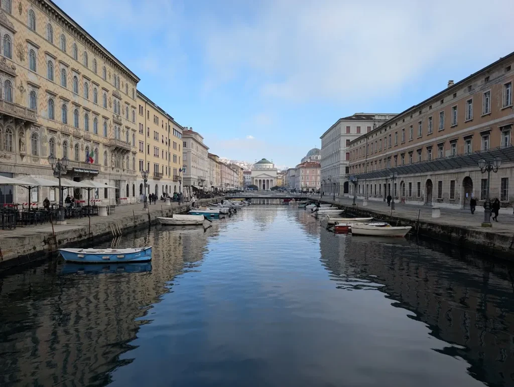 Canal Grande in Trieste with small boats moored along the waterway and grand neoclassical buildings on both sides, Italy