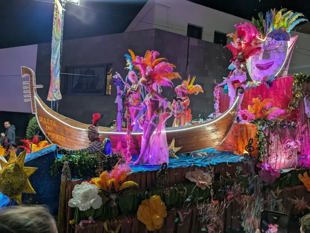 Colorful carnival float with costumed performers and feathered headdresses during the Câmara de Lobos carnival parade, Madeira