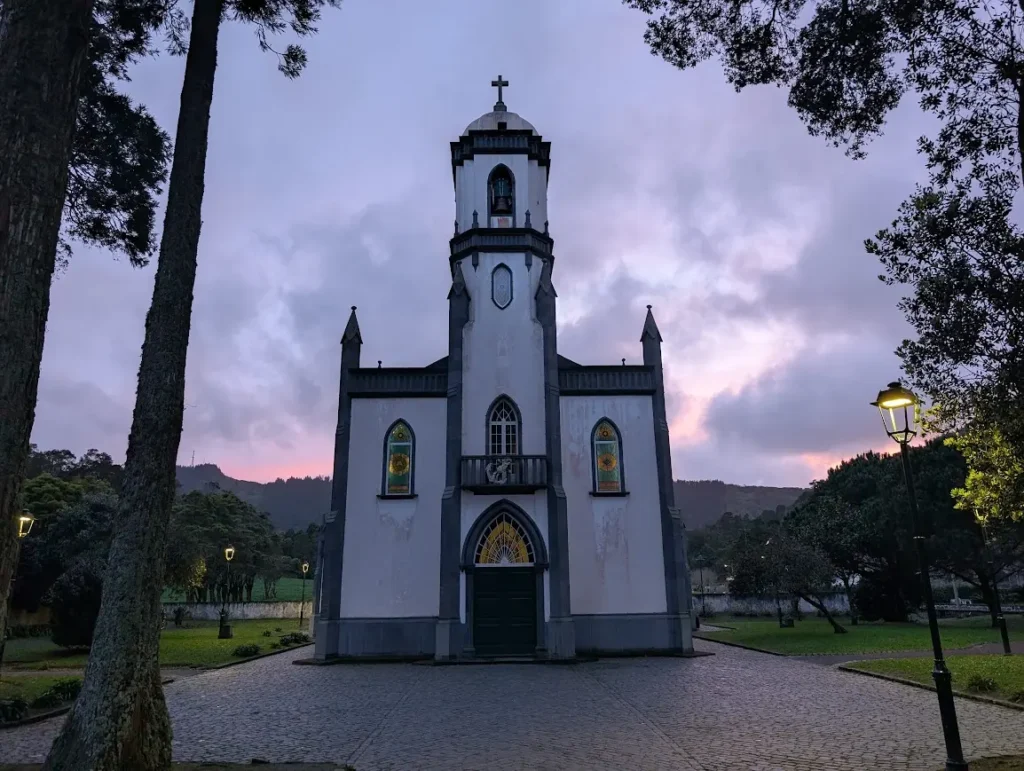 White and grey church with bell tower at dusk, pink clouds behind, Sete Cidades, São Miguel, Azores