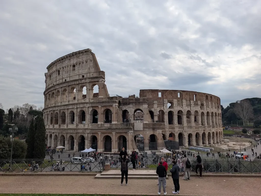 Exterior view of the Colosseum with tourists in the foreground on a cloudy day, Rome, Italy