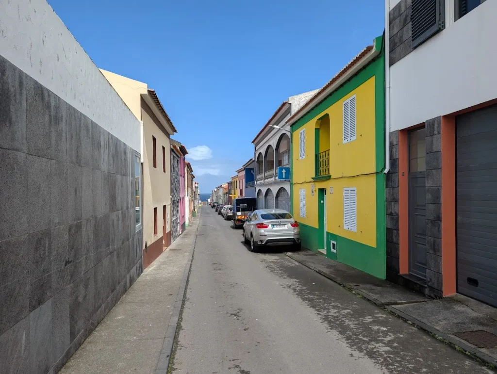 Narrow street lined with brightly painted yellow and green houses, Rabo de Peixe, São Miguel, Azores