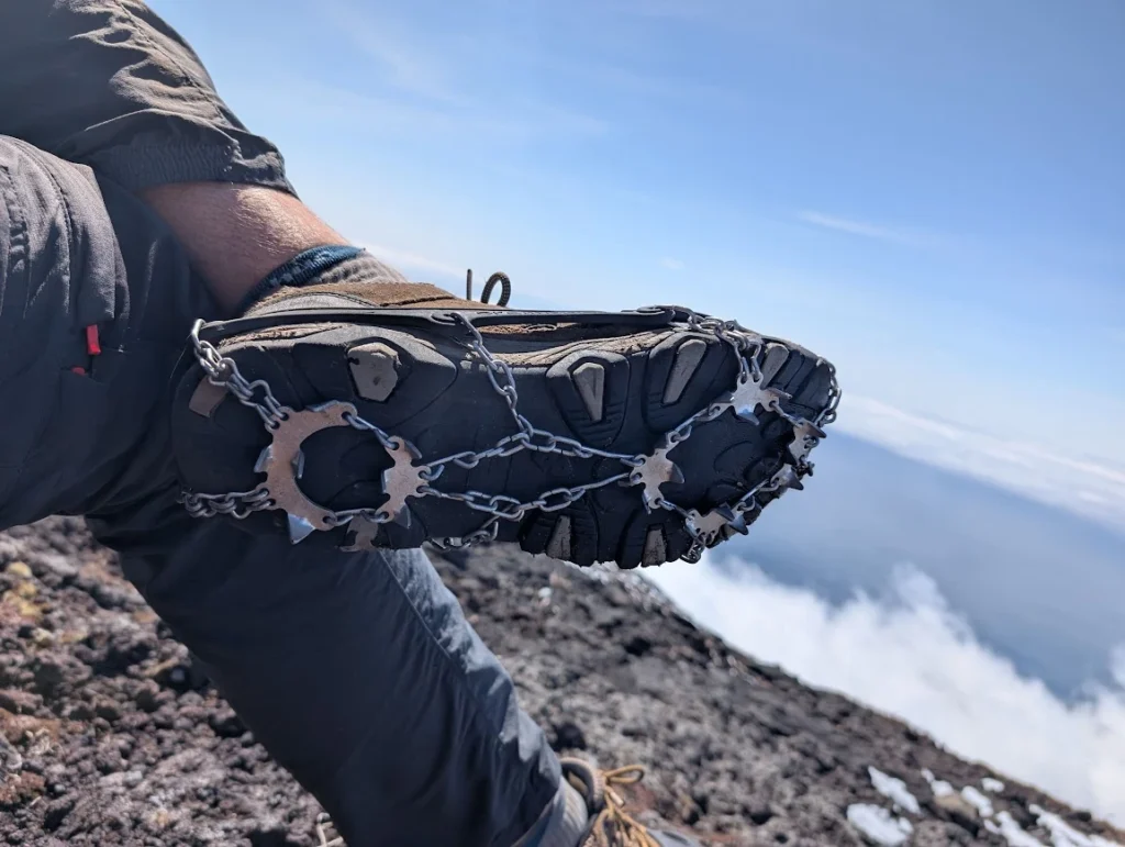 Crampons on hiking boot during Pico volcano climb, Azores, clouds below