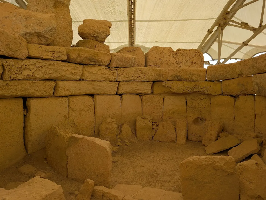 Interior limestone walls of Ħaġar Qim megalithic temple complex, southern Malta, protected by a tensile shelter roof.