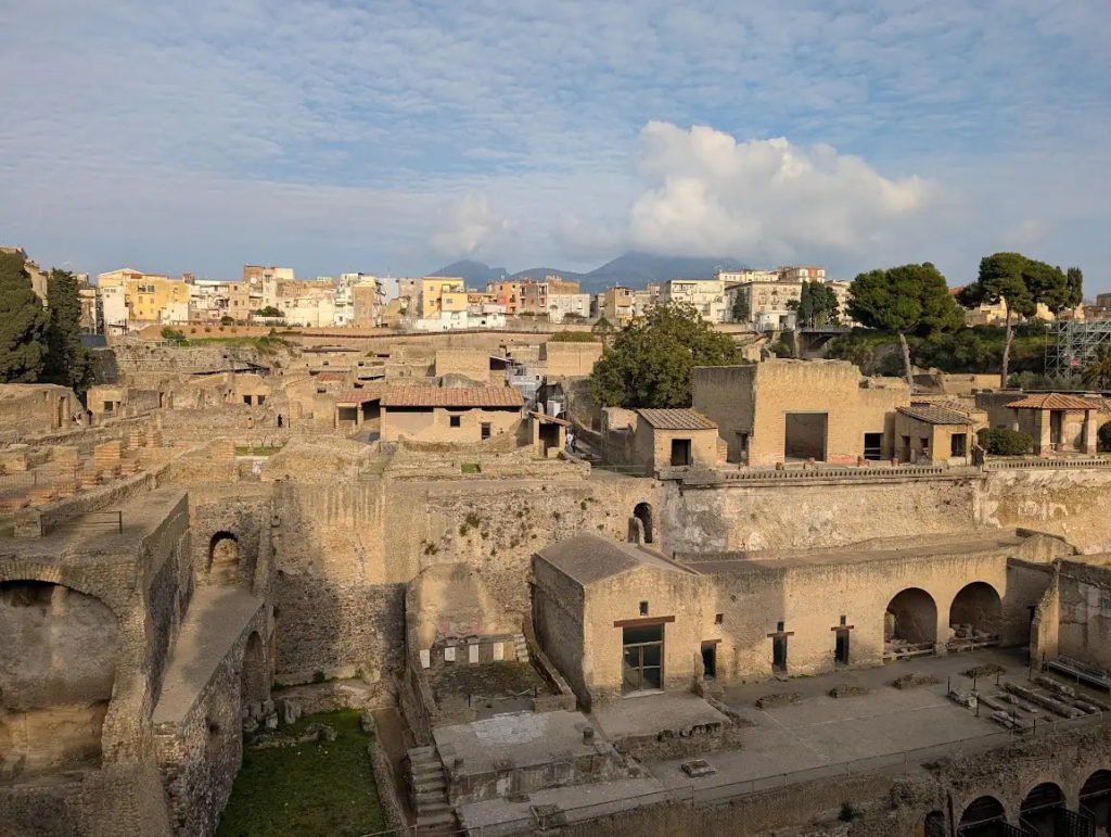 Overview of the Herculaneum archaeological site with ancient Roman buildings and Mount Vesuvius visible in the background, Naples, Italy