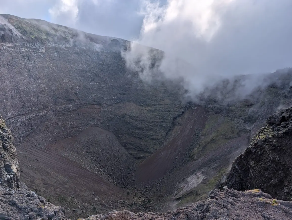View into the crater of Mount Vesuvius from the rim, with steam rising from the volcanic rock, Naples, Italy
