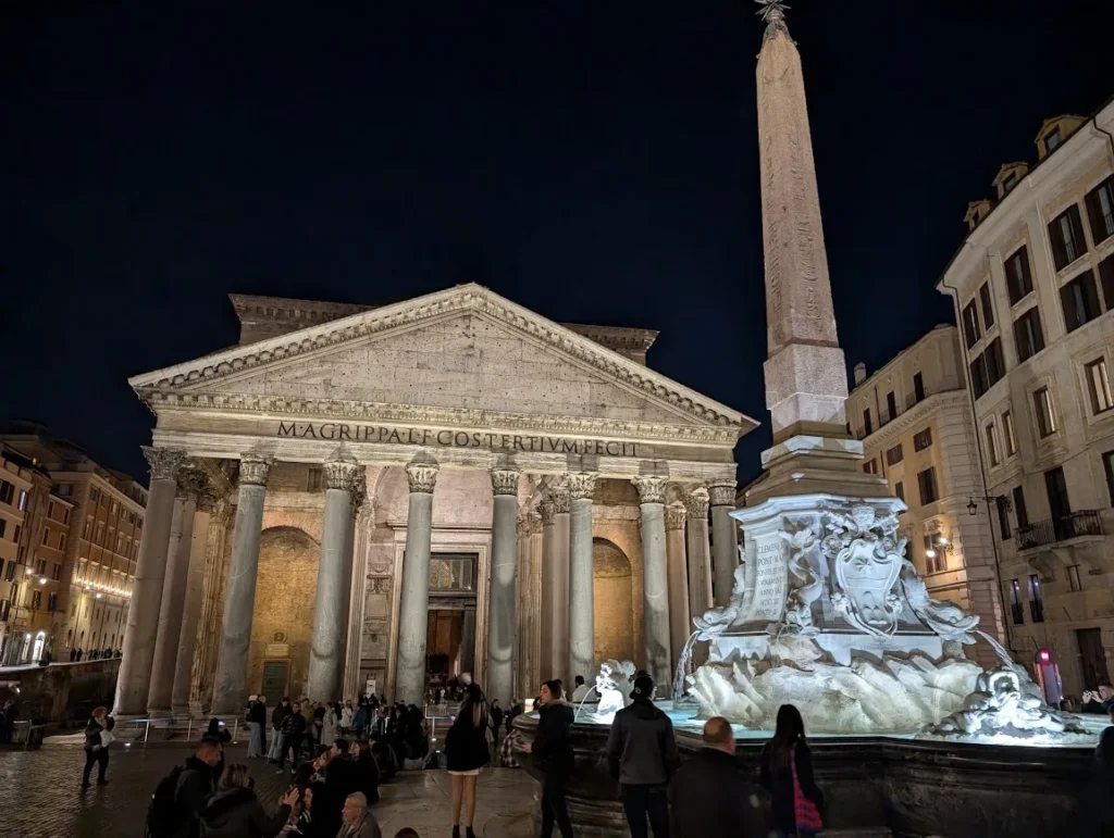 Pantheon illuminated at night with the Egyptian obelisk fountain in the foreground and crowds in Piazza della Rotonda, Rome