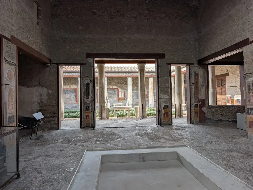 Interior of a Roman house in Pompeii with atrium, impluvium pool and colonnaded courtyard with frescoed walls, Italy