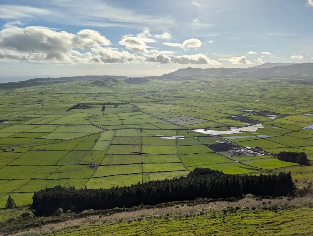 Aerial view of Terceira's patchwork green fields divided by dark volcanic stone walls, seen from Miradouro da Serra do Cume, Azores