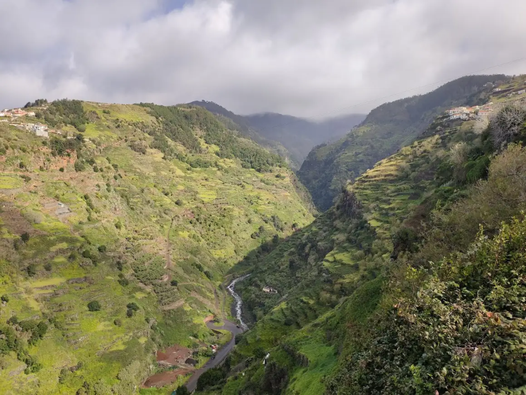 Terraced green valley with a narrow road and stream below, Madeira