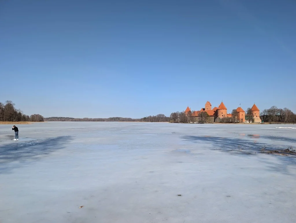 Trakai Island Castle viewed across a frozen lake in winter, with a person standing on the ice, Lithuania