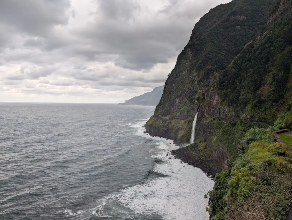 Véu da Noiva waterfall dropping from a cliff into a rough sea on Madeira's north coast