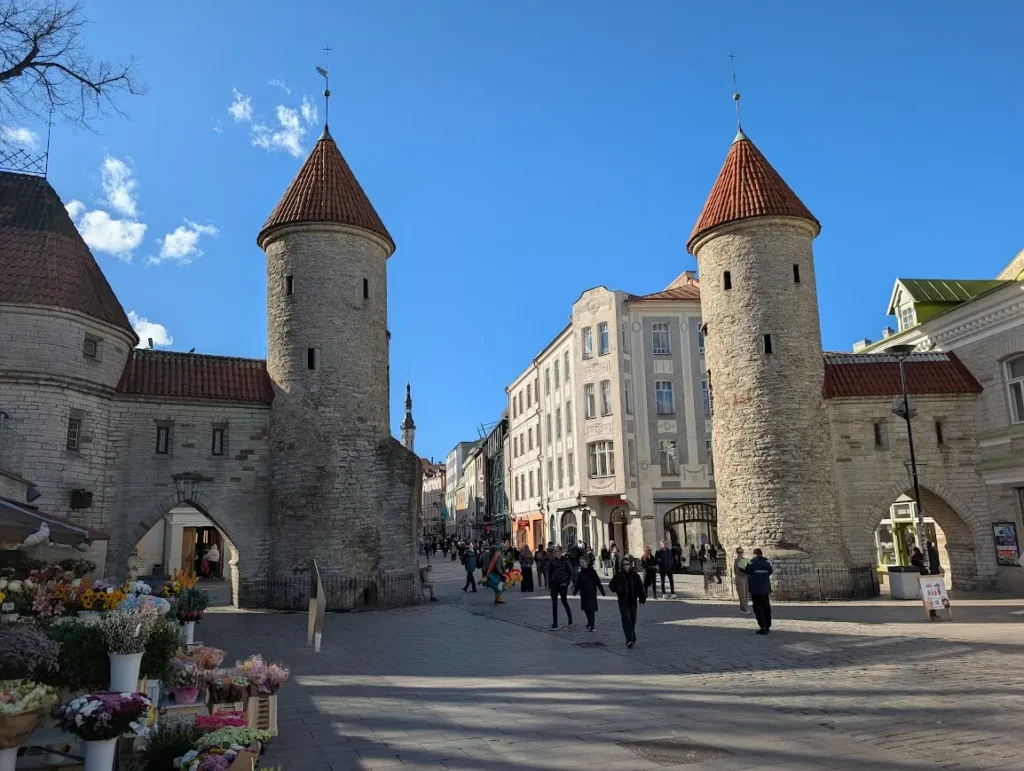 Medieval Viru Gate towers at the entrance to Tallinn old town, with flower stalls and pedestrians in the foreground, Estonia