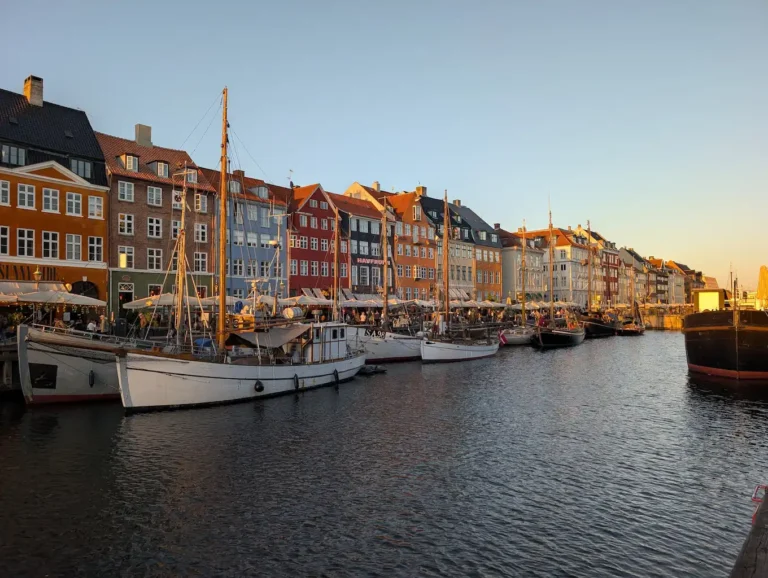 Colorful buildings and old wooden sailboats along Nyhavn canal in Copenhagen at sunset