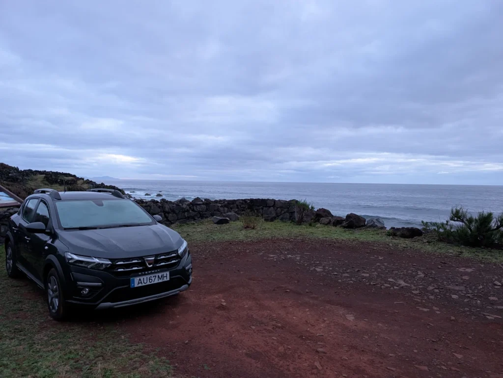 Black Dacia Sandero Stepway parked on red volcanic soil by the ocean, São Jorge, Azores