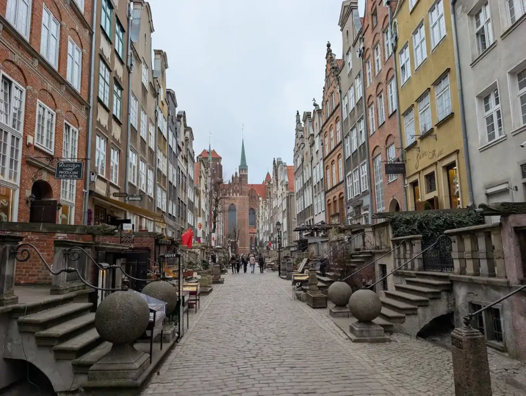 Historic street in Gdańsk Old Town with colorful merchant houses and St. Mary’s Church in the background