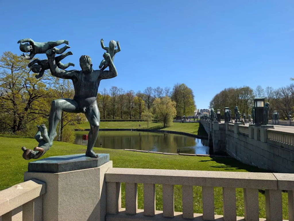 Vigeland Park in Oslo – bronze sculpture of a man surrounded by children, park bridge and pond in the background