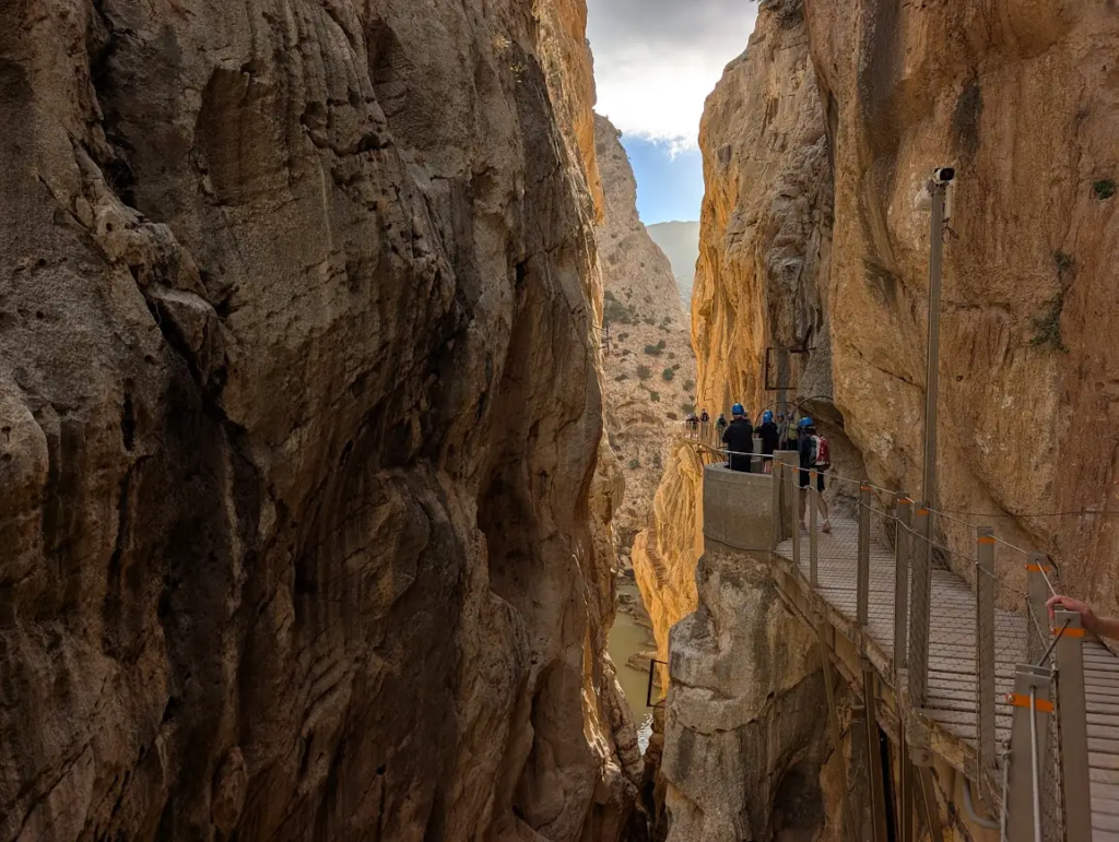 Caminito del Rey boardwalk inside the gorge, hikers visible ahead