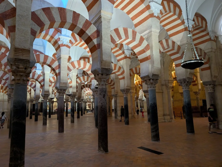 Interior of the Mezquita-Catedral de Córdoba with hundreds of columns and red and white striped horseshoe arches