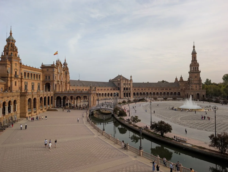 Wide view of Plaza de España with canal, bridges and twin towers at dusk, Seville, Spain