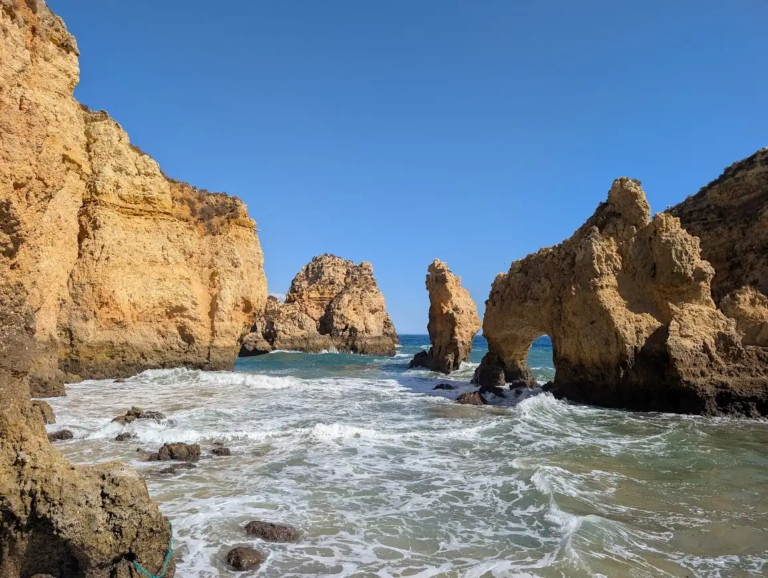 Golden limestone rock arches and sea stacks at Ponta da Piedade near Lagos, Portugal, with turquoise Atlantic water and waves breaking between the formations