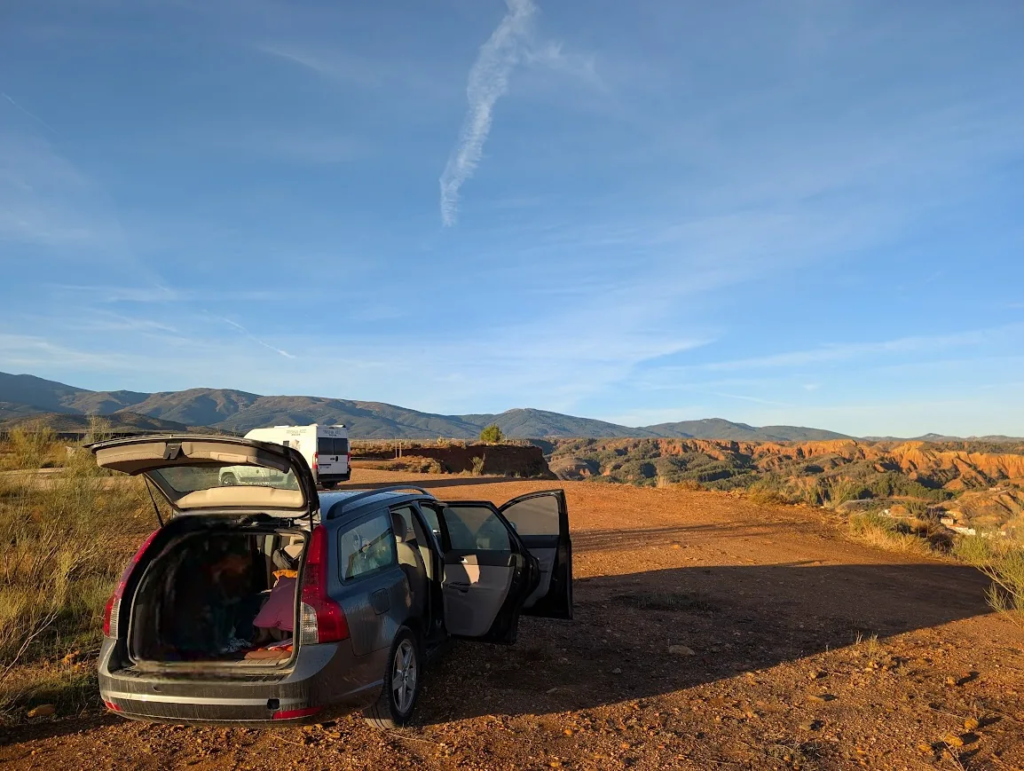 Volvo V50 rental car with trunk and doors open at Mirador del Fin del Mundo overlooking badlands near Guadix, Spain
