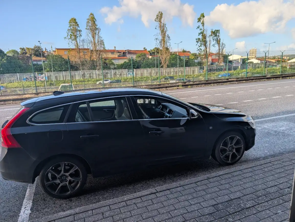Black Volvo V60 wagon parked roadside in Portugal, used for sleeping on a budget road trip