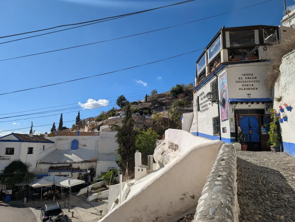 Whitewashed cave house with flamenco restaurant signage on a hillside in Sacromonte, Granada