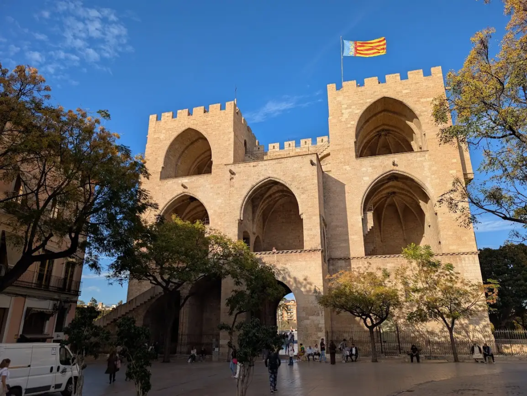 Torres de Serranos, a 14th-century Gothic city gate in Valencia, Spain, with people relaxing in the square below