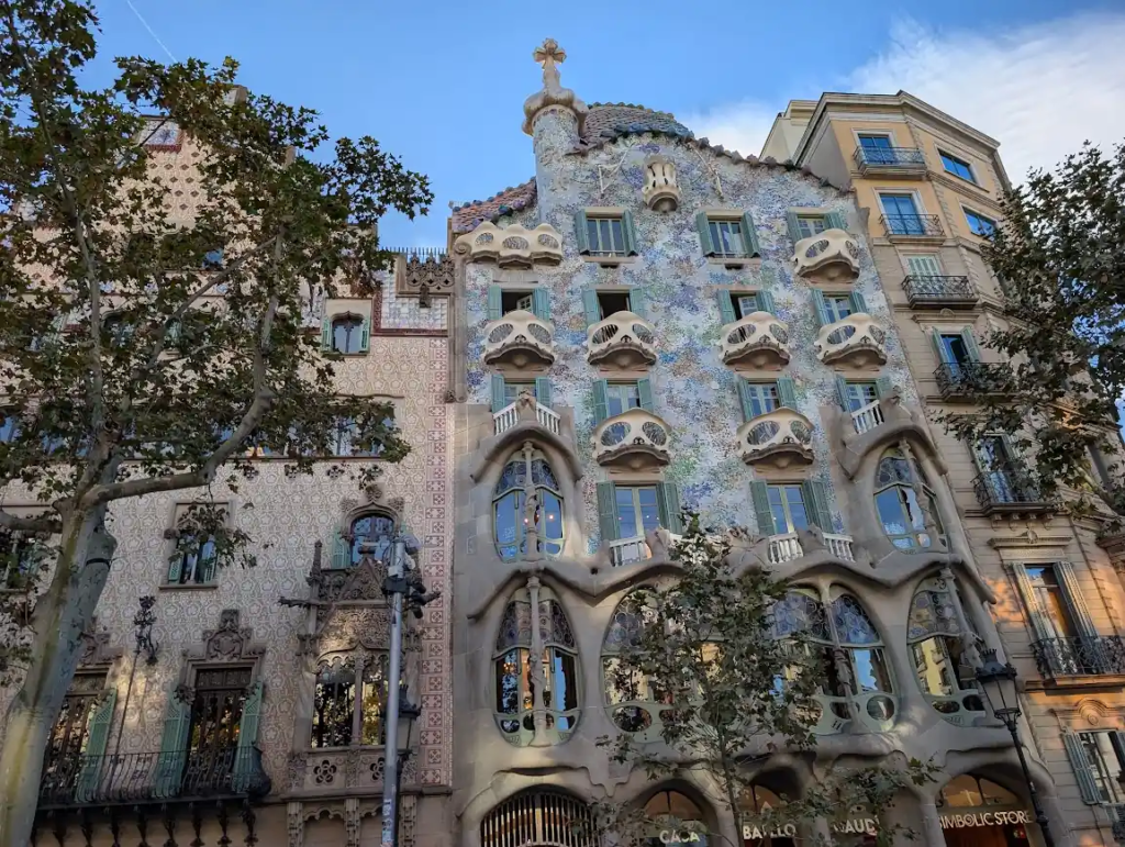 Casa Batlló facade in Barcelona, Gaudí's undulating balconies and mosaic tilework against a blue sky