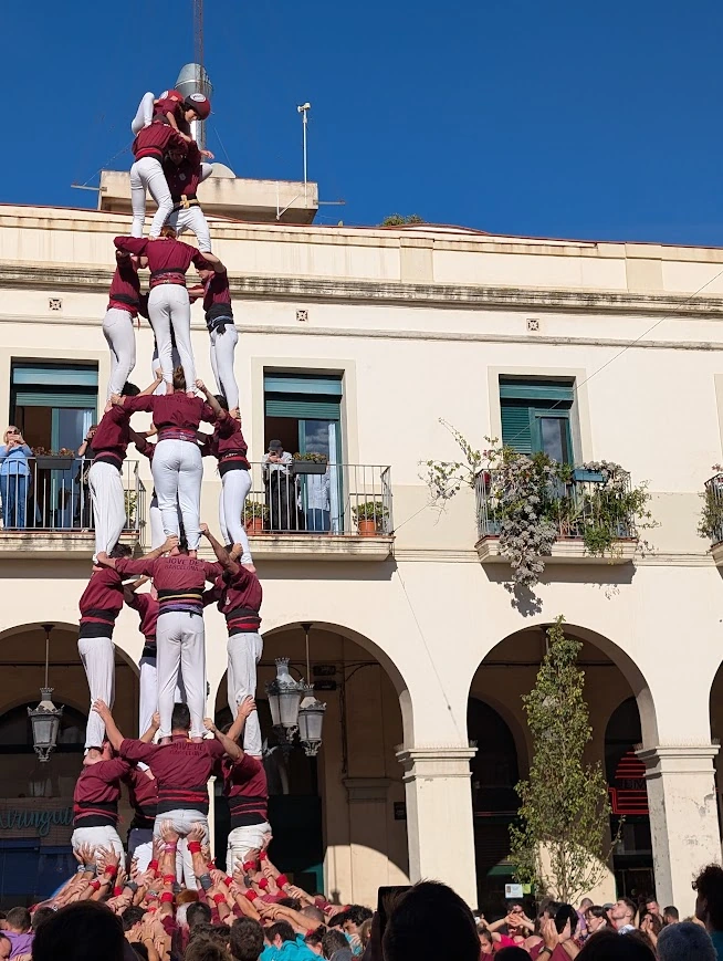 Castellers building a human tower in a town square in Catalonia, climbers scaling the stacked formation