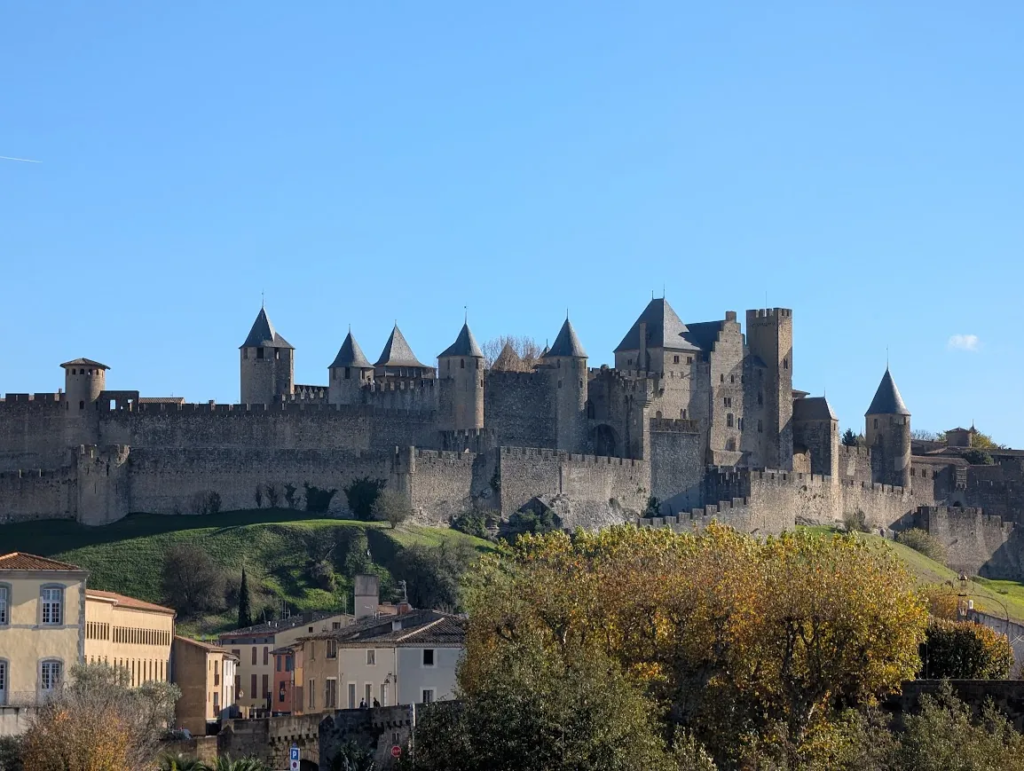 Fortified medieval city of Carcassonne in southern France, with its double walls and conical towers above autumn trees on a clear November day