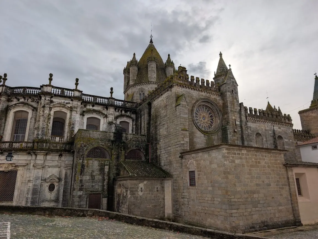 Granite exterior of the Sé Cathedral in Évora, Portugal, with a rose window and crenellated towers