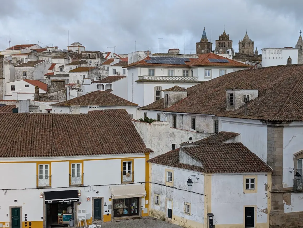 Terracotta rooftops and whitewashed houses in the old town of Évora, Portugal, under a cloudy sky