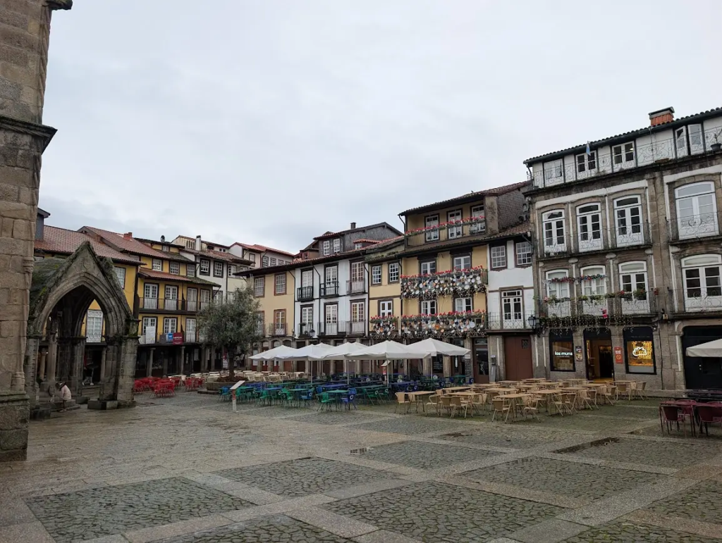 Empty cafe tables in a rainy cobblestone square in the medieval center of Guimarães, Portugal