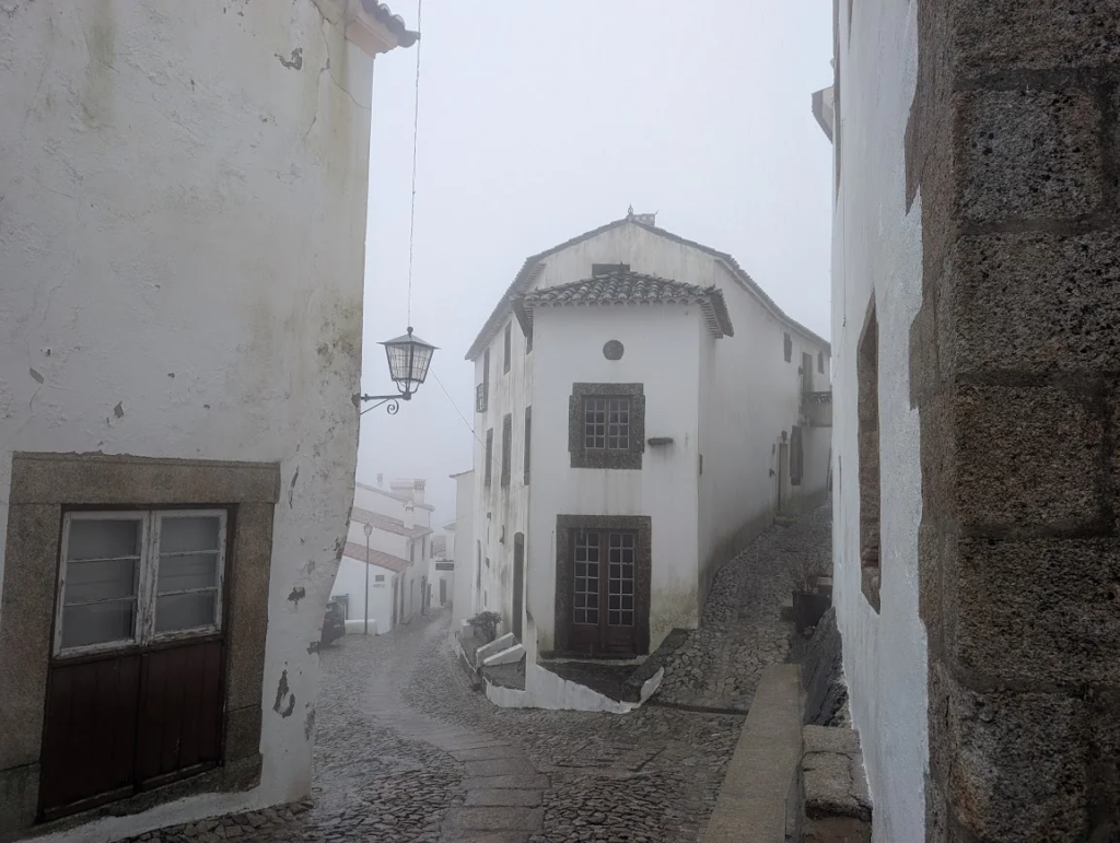 Cobblestone street between whitewashed houses in Marvão, Portugal, in thick fog