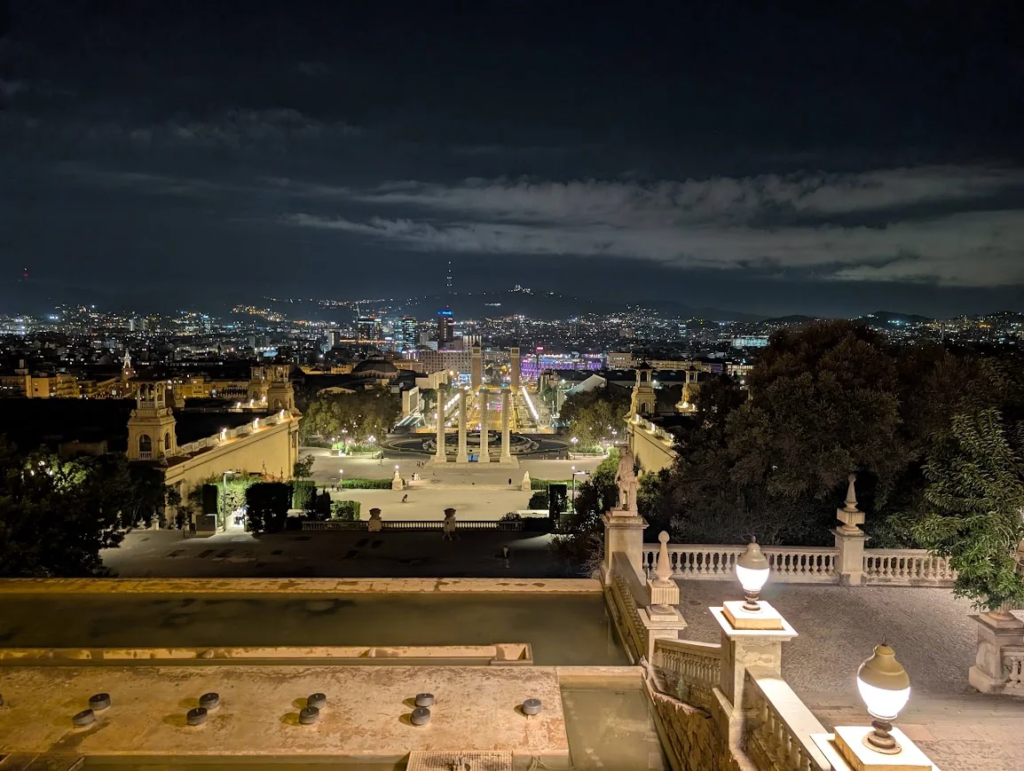 Night view from Montjuïc over Barcelona's Magic Fountain and Plaça d'Espanya, city skyline lit up in the distance