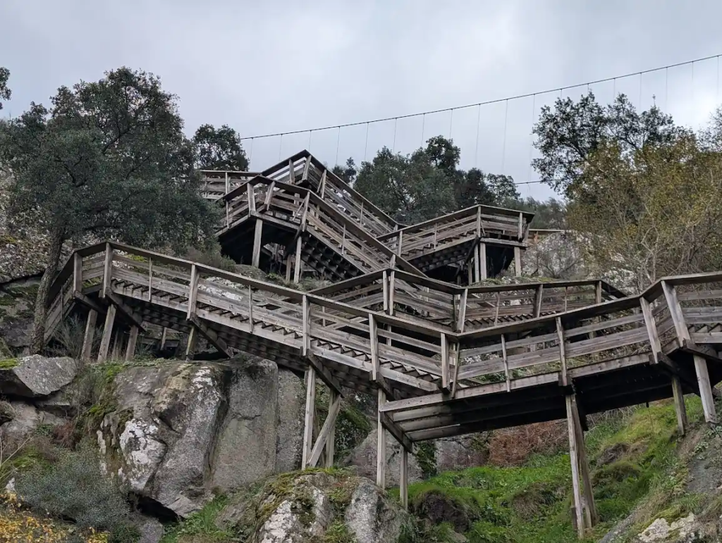 Wooden boardwalk stairs on the Passadiços do Paiva trail near Arouca, Portugal, with the suspension bridge cable above