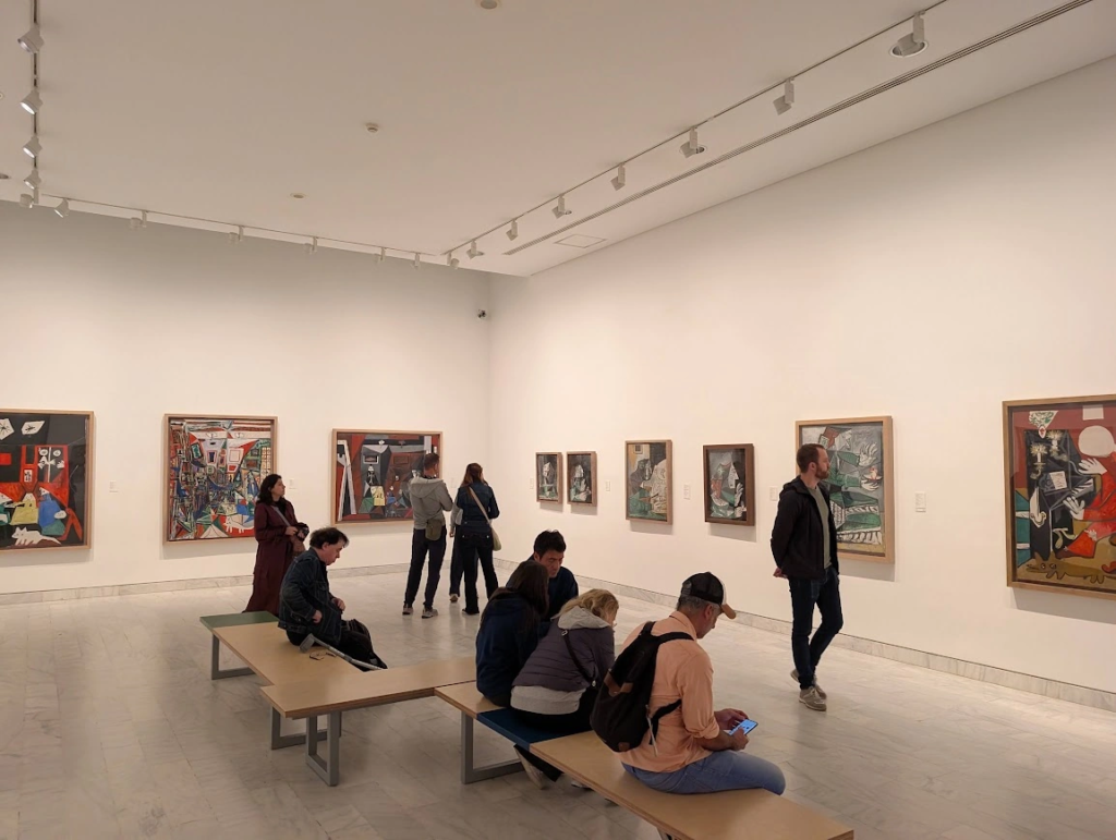 Gallery room at the Picasso Museum in Barcelona with visitors viewing Cubist paintings on white walls