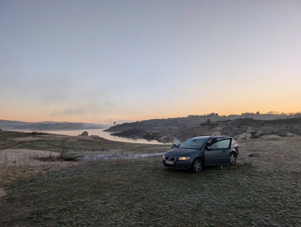 Volvo V50 station wagon parked on frosty grass beside a lake at sunrise in northern Portugal