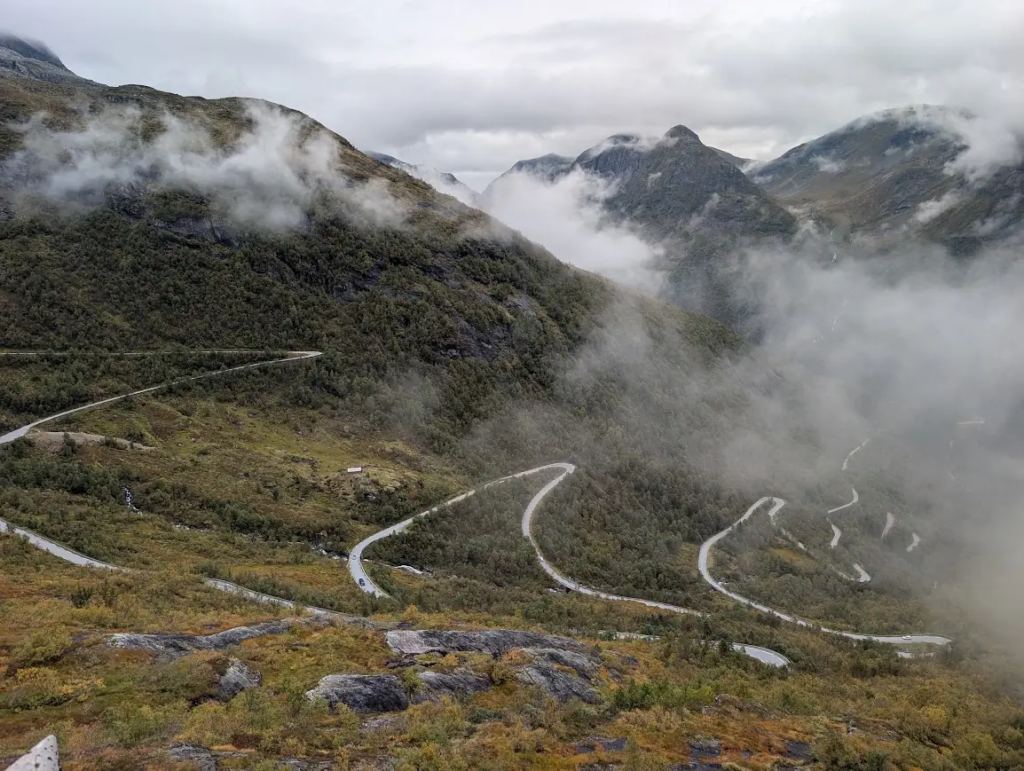Winding hairpin road climbing a misty mountainside with low clouds on the Gaularfjellet scenic route in Norway
