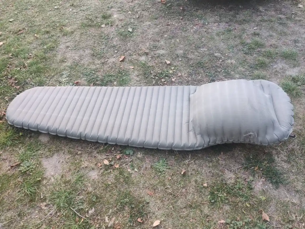 Therm-a-Rest NeoAir XLite sleeping pad lying on grass with a large delamination bulge at one end